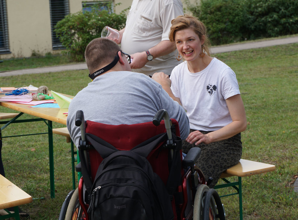 Mann im Rollstuhl mit Workshopleiterin am Basteltisch